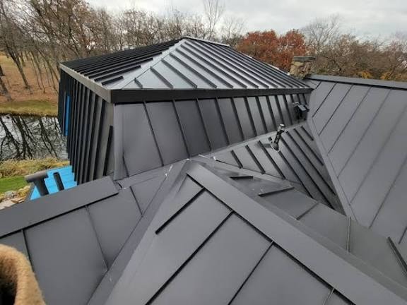 Dark standing-seam metal roof with intersecting planes and custom valley flashing