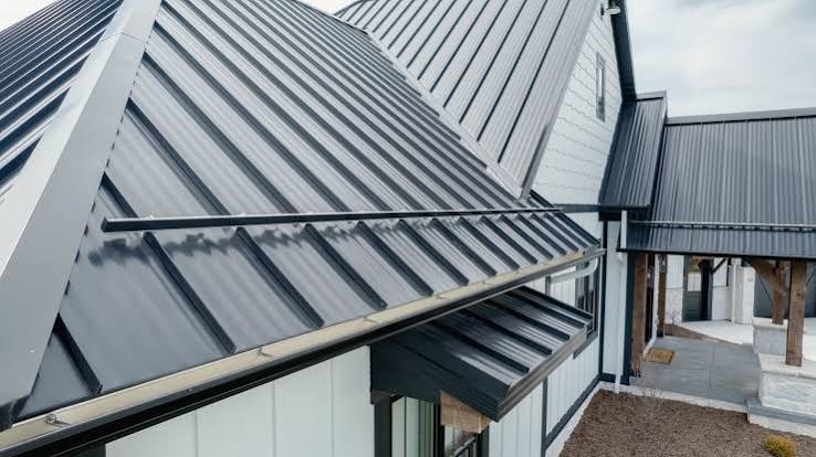 Finished dark standing-seam metal roof with detailed flashing and intersecting roof sections