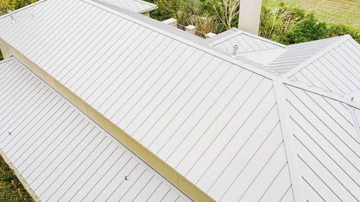 Light standing-seam metal roof showing intersecting roof planes and detailed seams